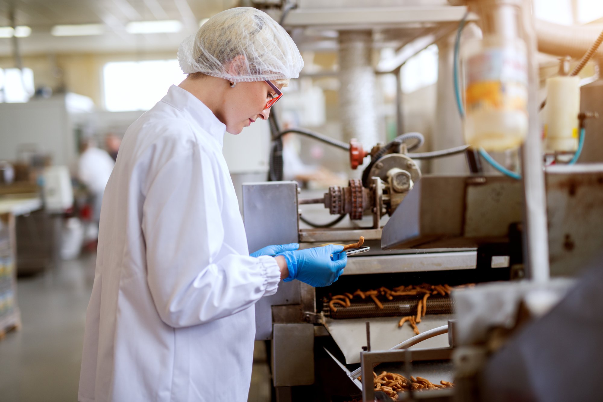close-up-view-young-female-worried-worker-sterile-cloths-inspecting-salt-sticks-taken-from-food-snack-production-line close-up-view-young-female-worried-worker-sterile-cloths-inspecting-salt-sticks-taken-from-food-snack-production-line