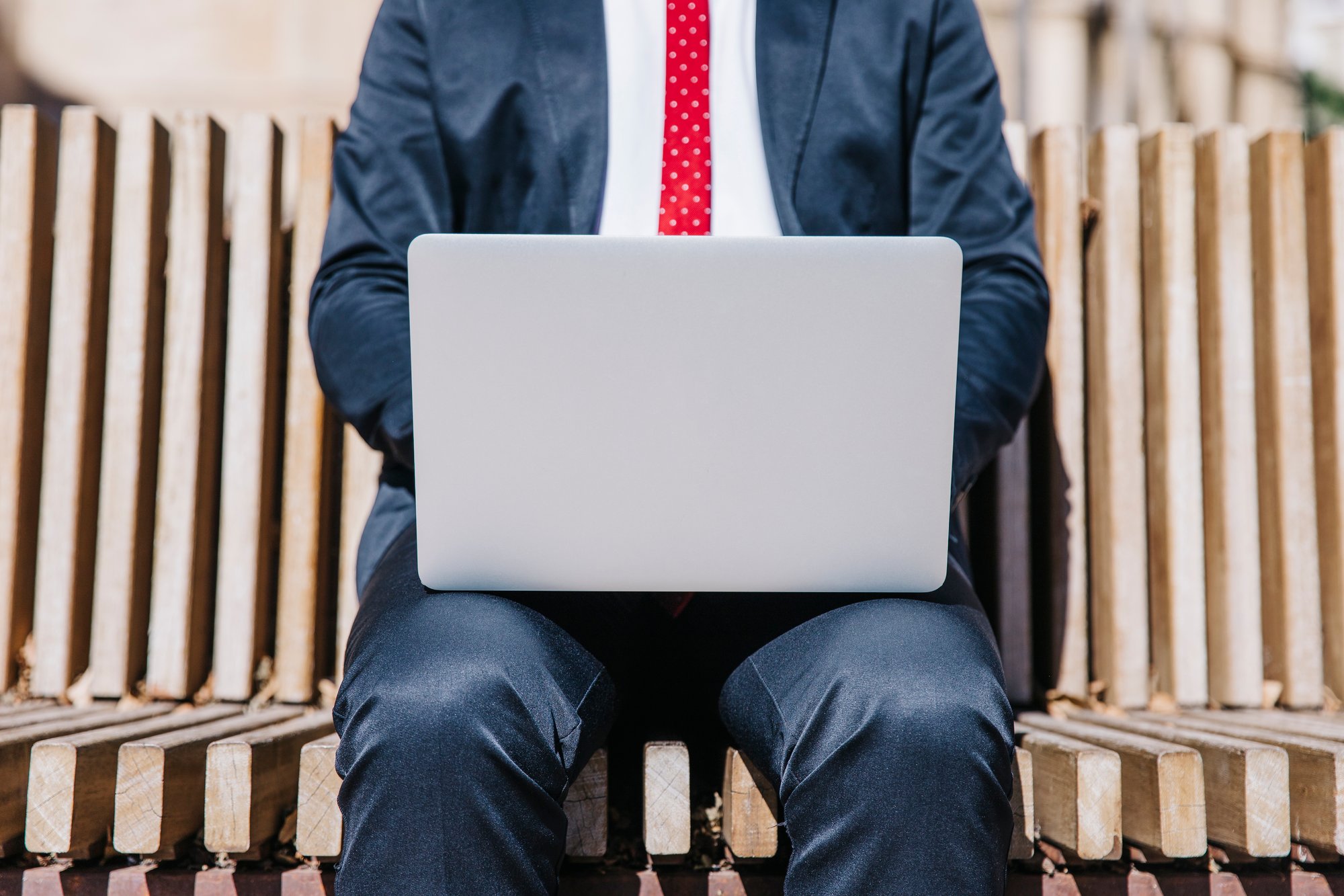 crop-businessman-browsing-laptop-bench