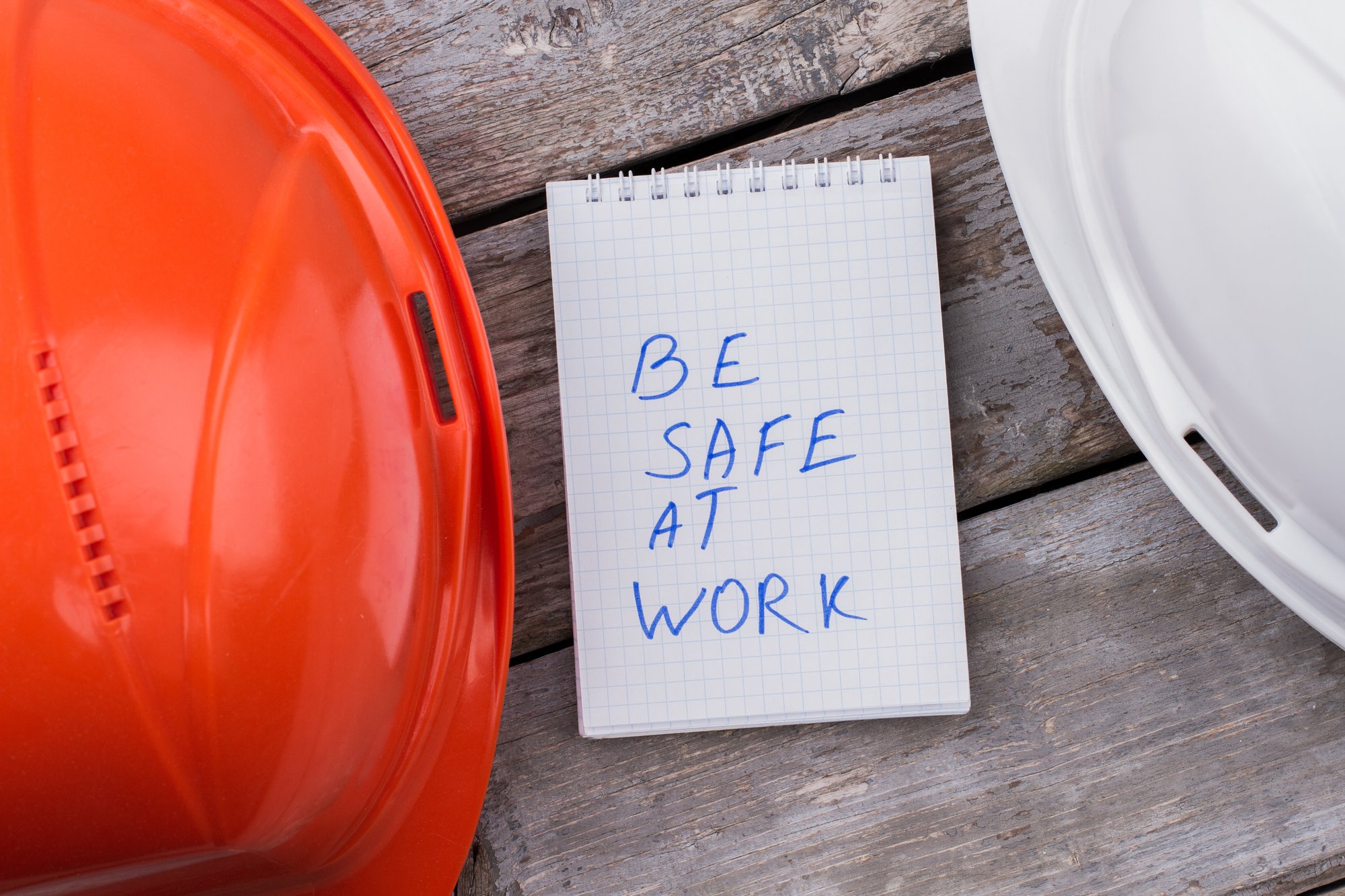 be-safe-work-concept-white-orange-constructor-helmets-notepad-with-be-safe-work-notice-wooden-table be-safe-work-concept-white-orange-constructor-helmets-notepad-with-be-safe-work-notice-wooden-table